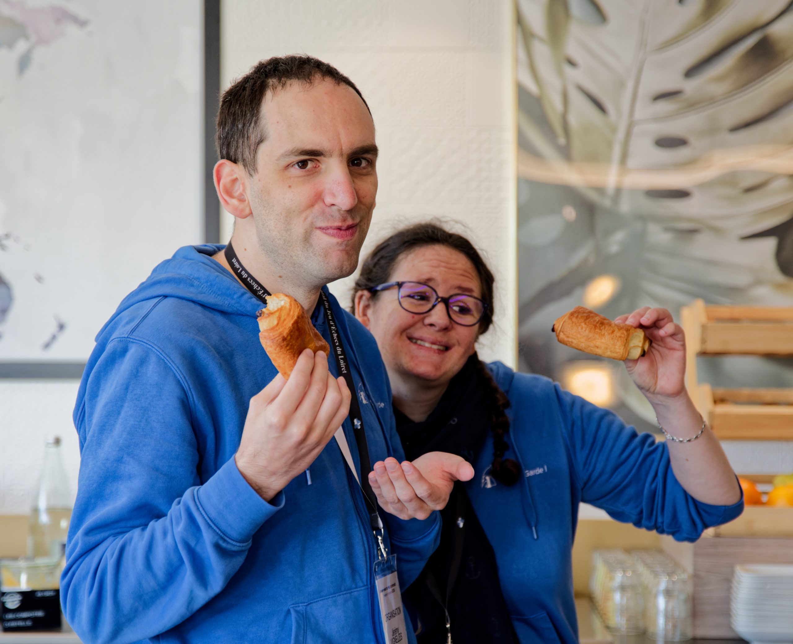 Aurélie et Jérémy posent fièrement, face caméra avec un pain au chocolat à la main.